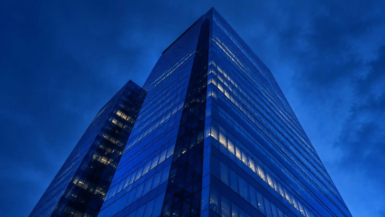 Glass skyscraper against a deep blue evening sky